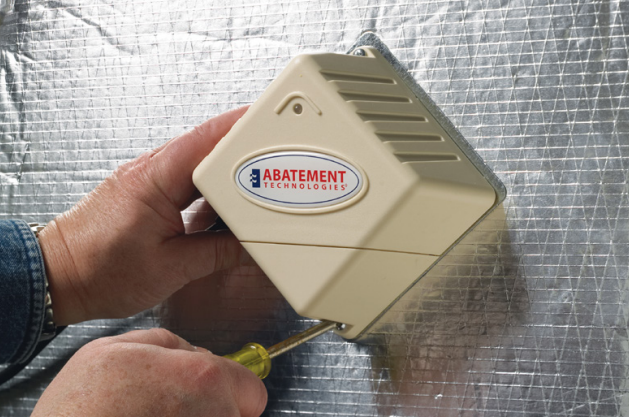 Hand holding an Abatement Technologies Air Purifier Installed on Ductwork