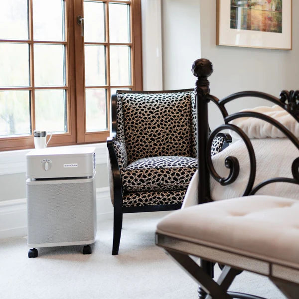 Room interior with a leopard print chair, white ottoman, and a small appliance on a white floor.